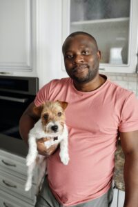 A man is holding a terrier puppy in his kitchen at home