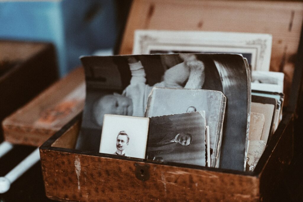 An old wooden box is open, showing stacks of old black and white photos inside.