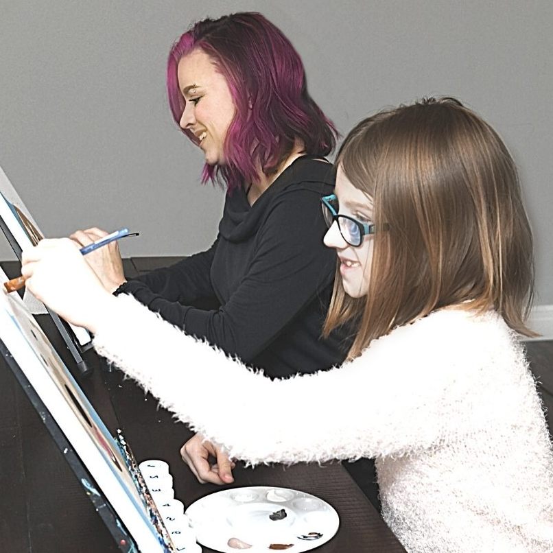 Mom and daughter painting their pet portraits together smiling and happy.
